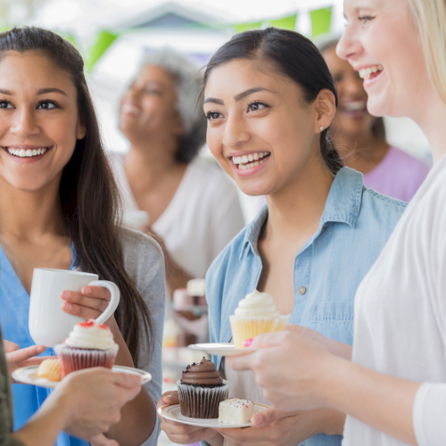A group of friends with coffee cups smiling together at a cafe.