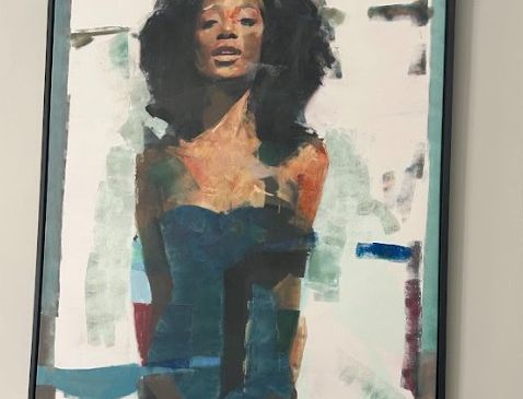 A framed abstract portrait of a woman with curly hair in bold colors, standing against a mixed light background with blue and orange accents.