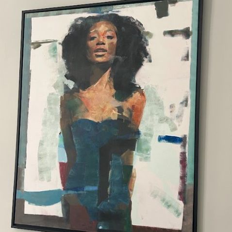 A framed abstract portrait painting of a woman with stylized facial features and colorful blocks in the background.